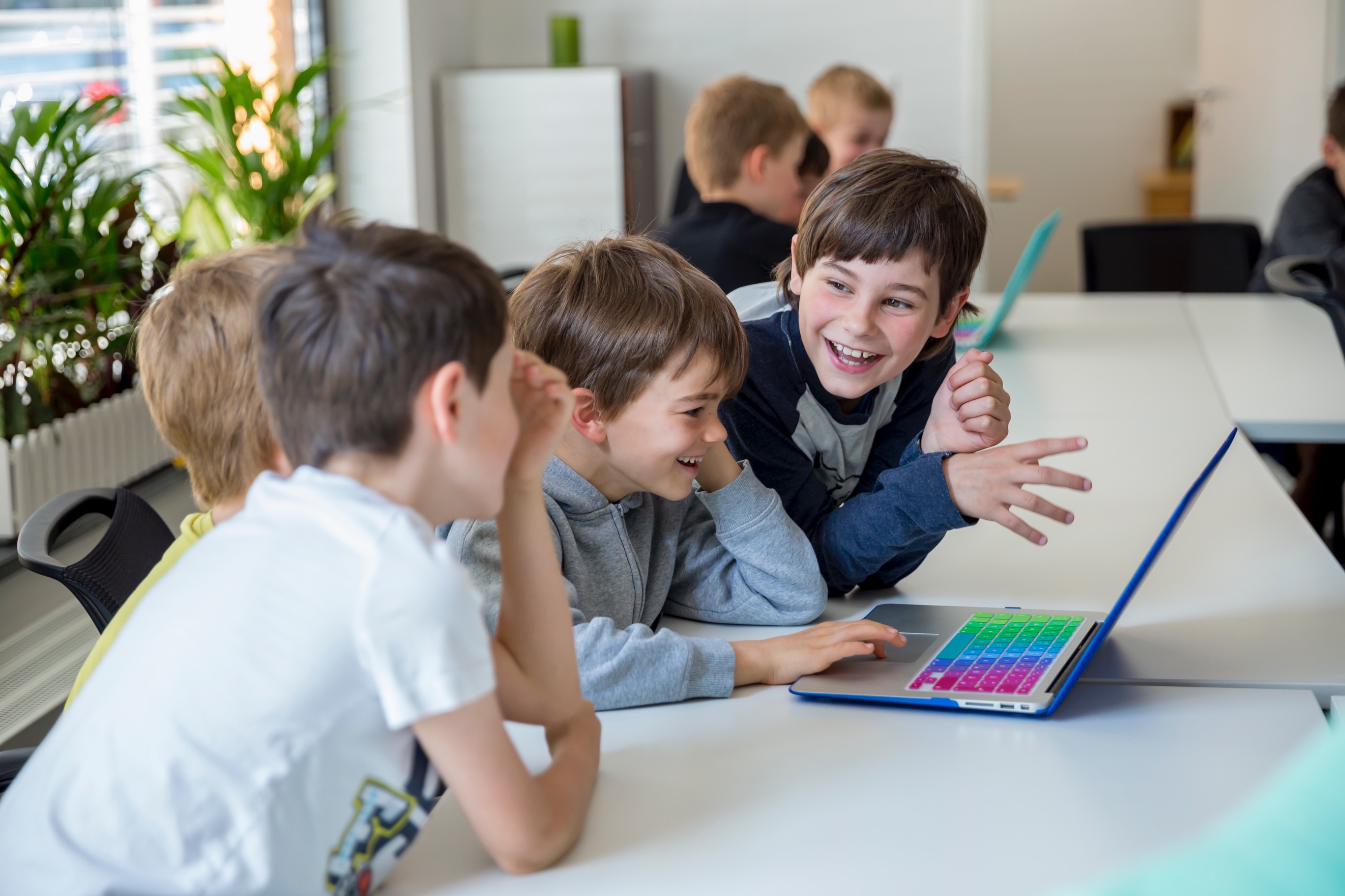 Kinder lachen gemeinsam vor einem Laptop im Workshop